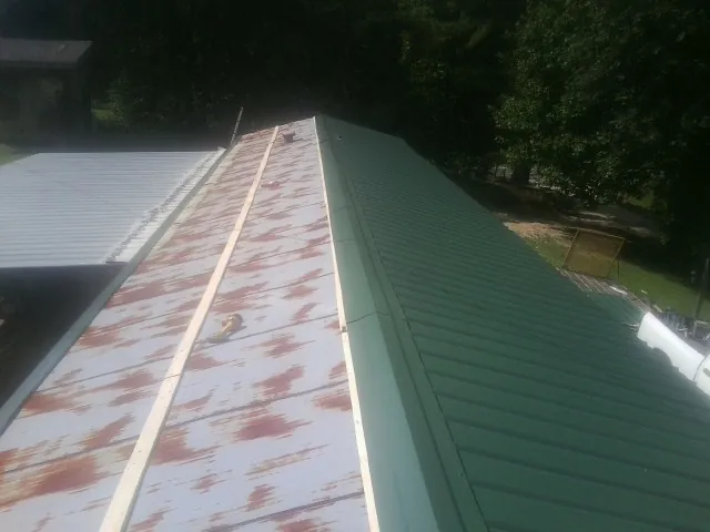Old rusted panels beside newly installed green metal roofing — Wind Damage Roof Repair by Roofing Brothers in Harwich Port
