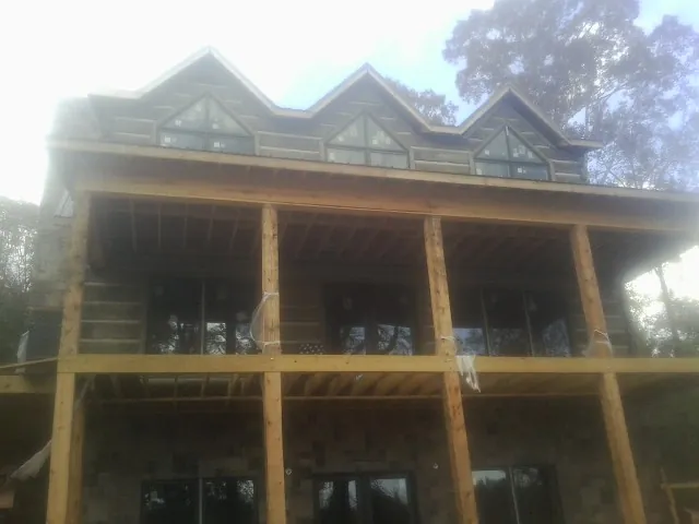 Dormers and porch framing on a large log home under construction — Roof Coating work by our crew in Harwich Port