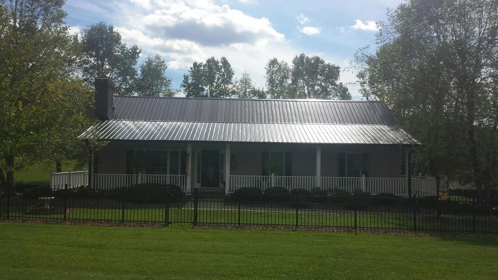 Gray metal roof on a brick ranch with a full width front porch — Gutter Guard Installation work by our crew in Harwich Port