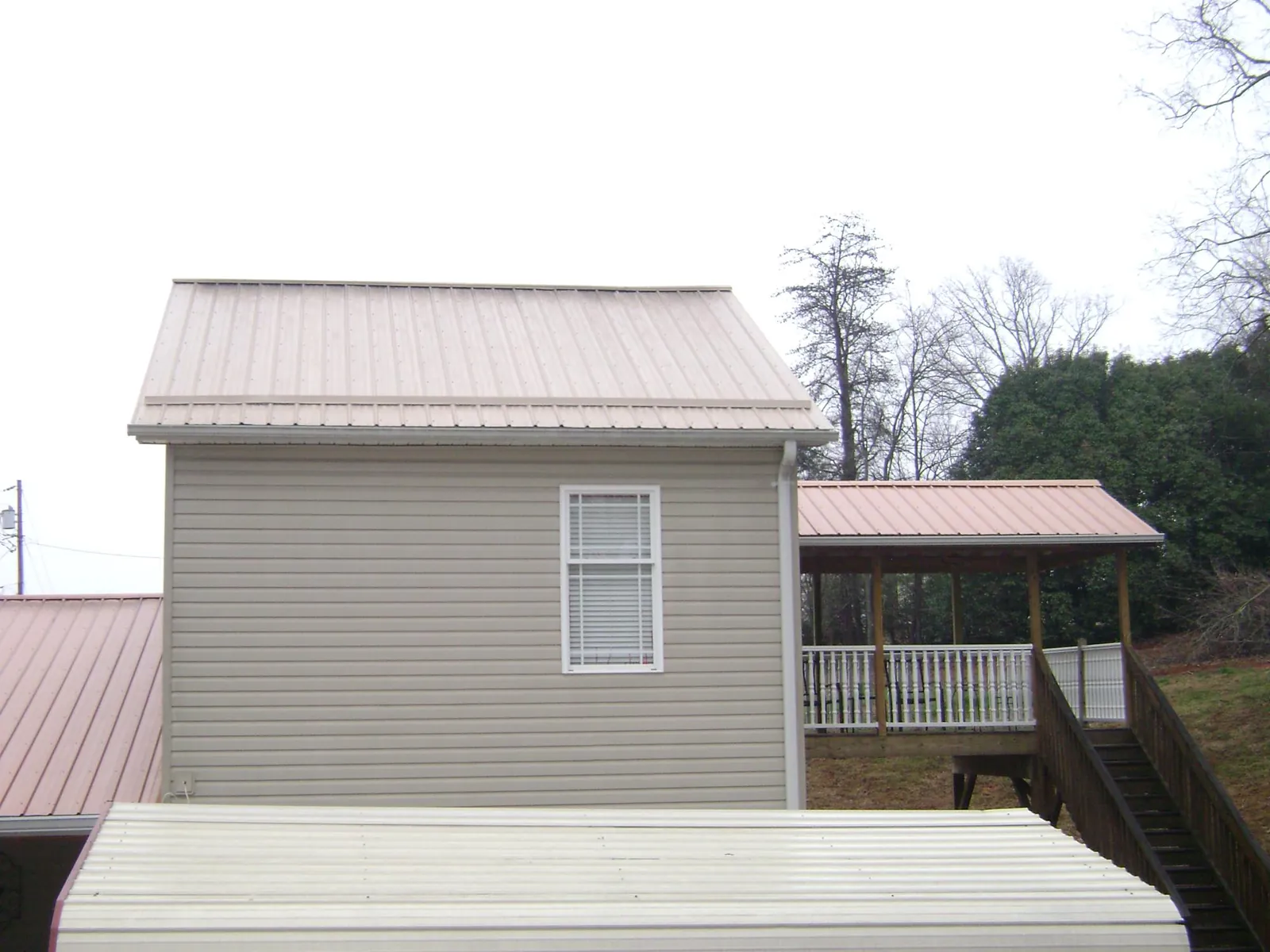 Tan metal roofs on a two story addition and attached porch, from a Roof Replacement job in Harwich Port