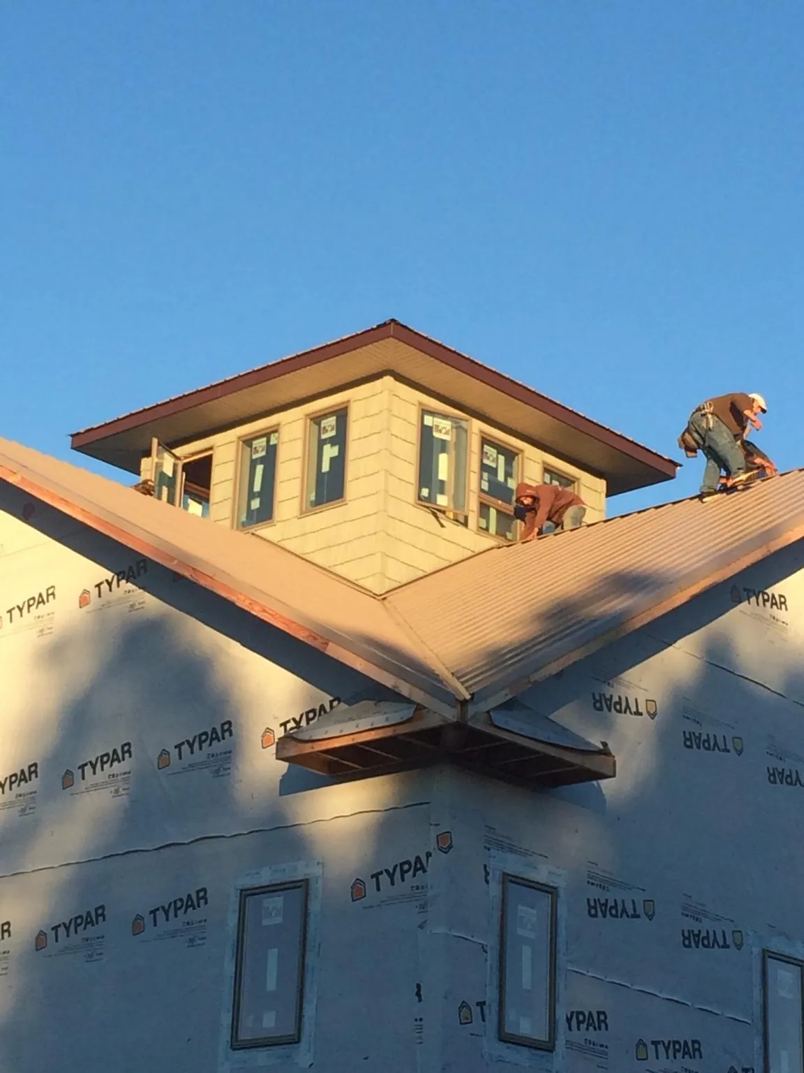 Roofers working around a rooftop cupola on a new metal roof at sunset — Roof Waterproofing in Harwich Port by Roofing Brothers